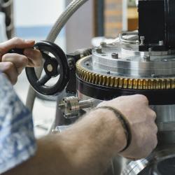 Two hands operating a silver piece of scientific equipment. 