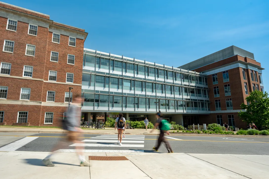 Blurred people walking in front of a red brick and glass building