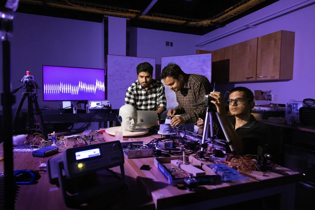 Three people working in a dark lab