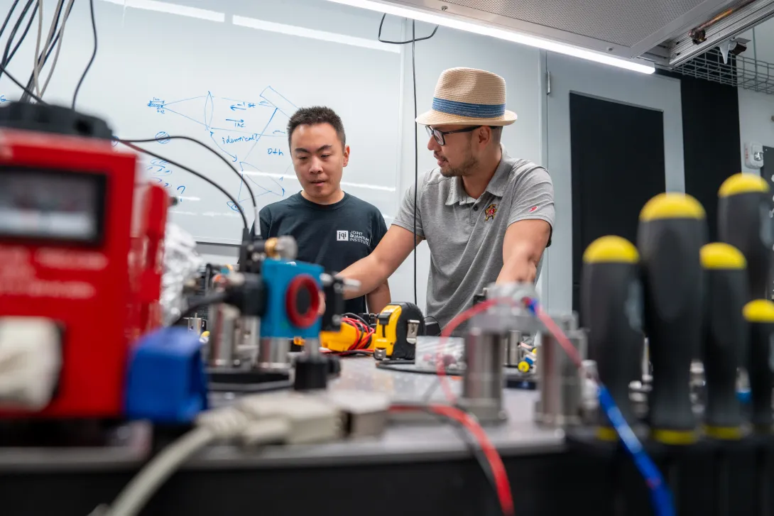Two people working at a lab bench on a machine instrument