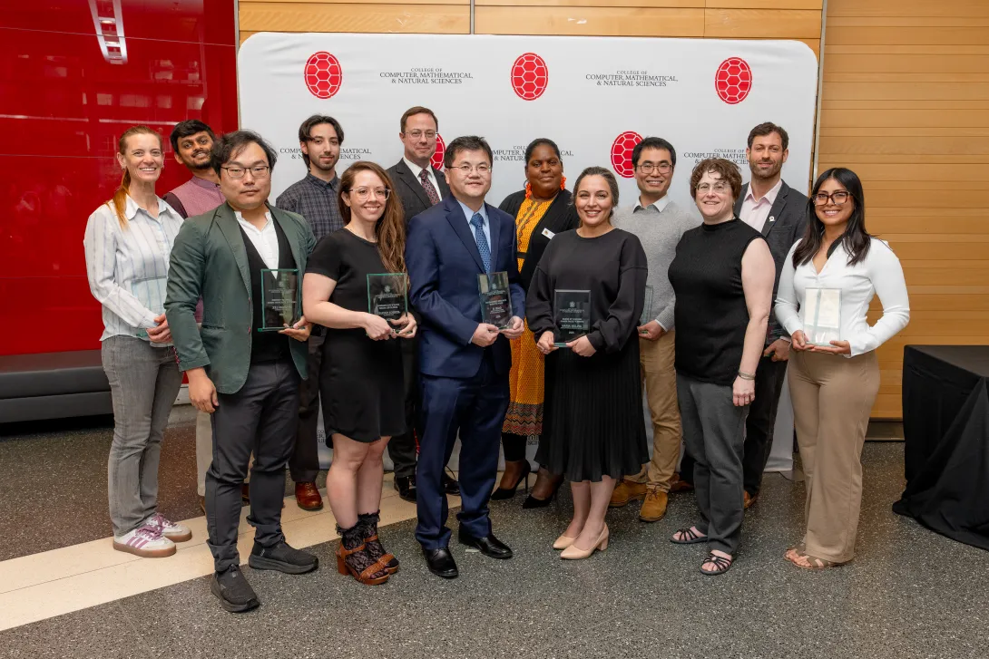 Group of people holding awards in front of a step-and-repeat banner