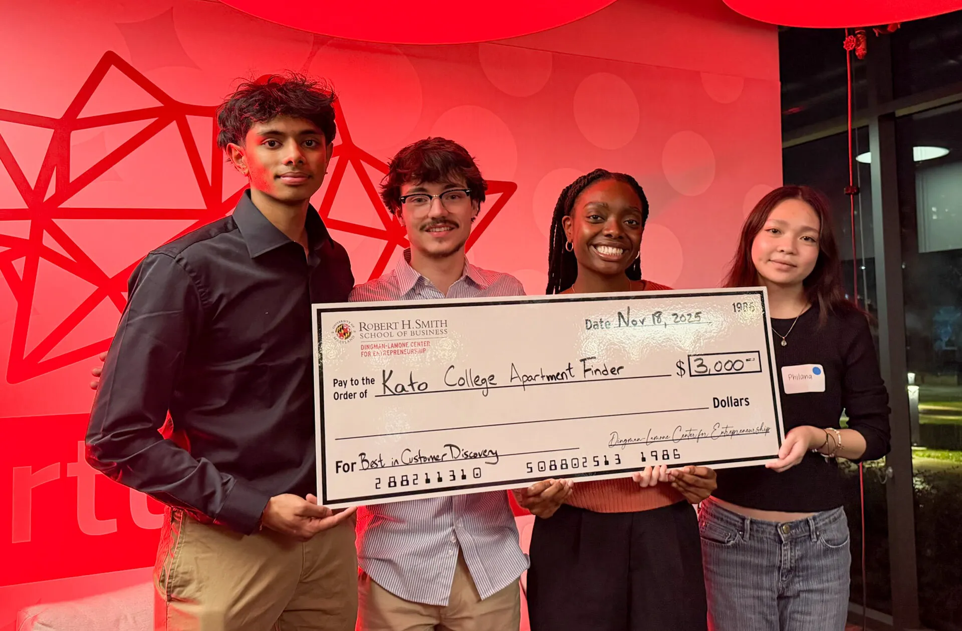 Four students hold up a large check.